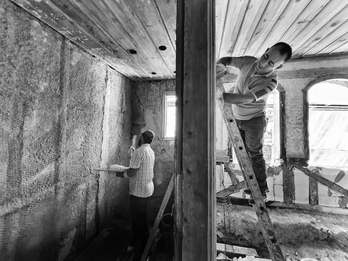 Two technicians repairing interior walls, one working from a ladder