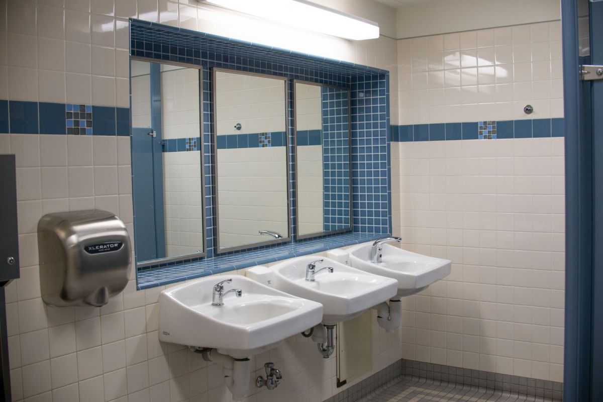 Row of sinks and a hand dryer in a tiled commercial restroom
