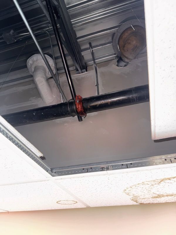 Suspended ceiling opened beside water-stained ceiling tiles