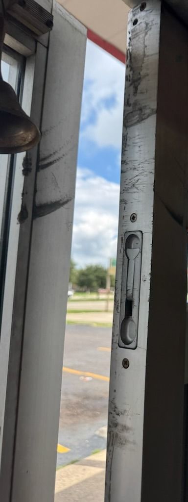 Scraped and dented aluminum door stile with its lock strike