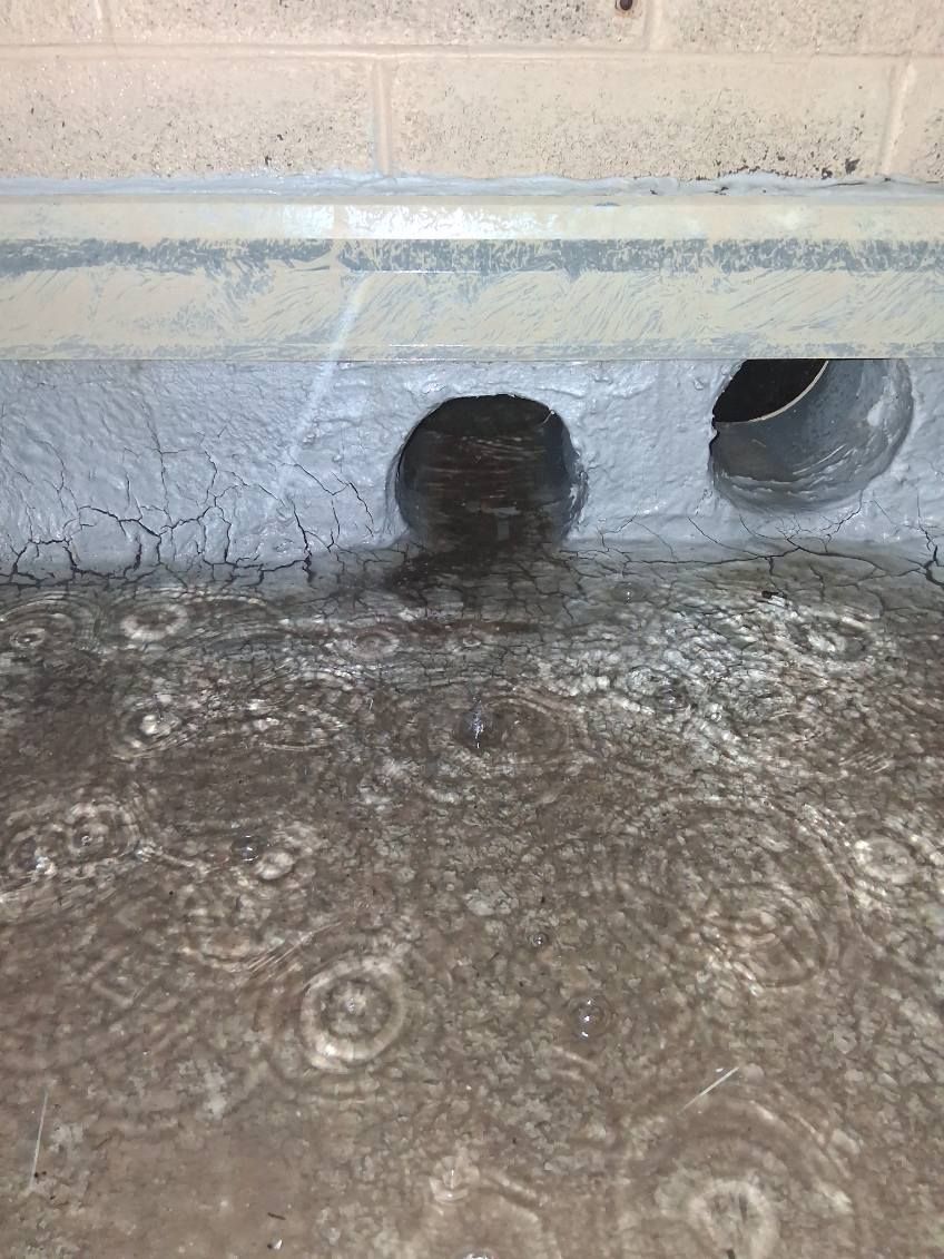 Water backed up at a blocked scupper opening in a parapet wall