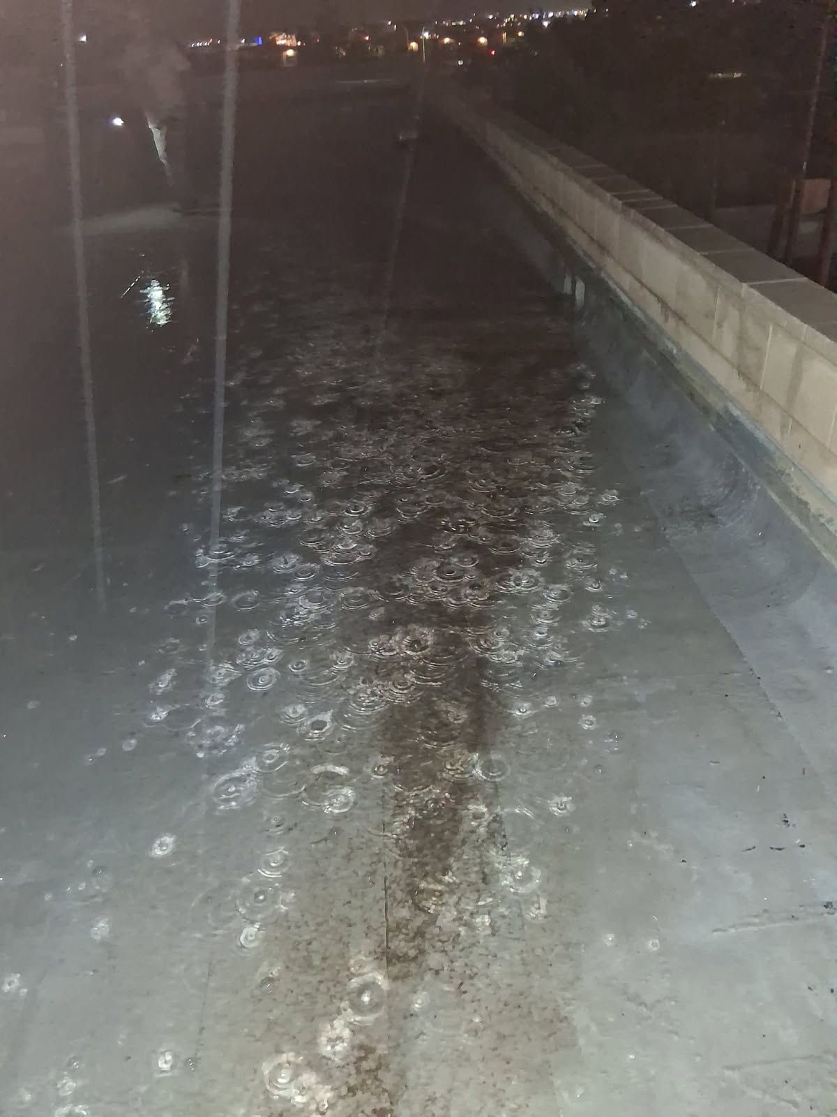 Rain pooling across a flat commercial roof at night