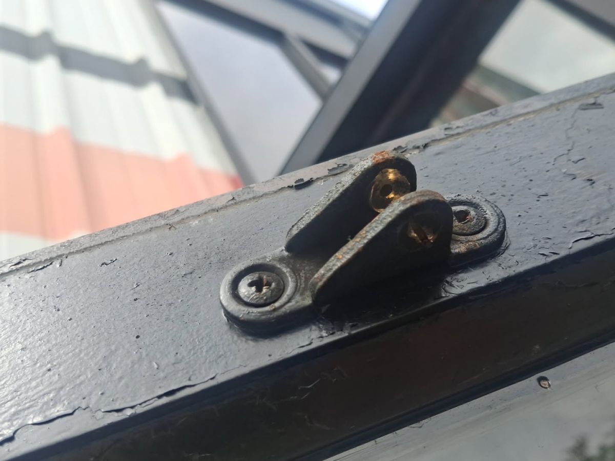 Worn hinge bracket on a storefront window frame